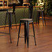 A Lancaster Table & Seating black metal barstool with a gray wood seat.