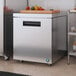 A stainless steel Hoshizaki undercounter refrigerator with vegetables on top.