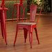 A Lancaster Table & Seating red metal chair with a gray wood seat in a restaurant dining area.