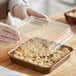 A person holding a clear plastic container with a cake inside.