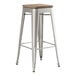 A Lancaster Table & Seating metal barstool with a gray wood seat.