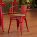 A red metal Lancaster Table & Seating arm chair with a gray wood seat.