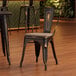 A Lancaster Table & Seating black metal chair with a gray wood seat at a table in a restaurant.