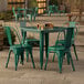 A Lancaster Table & Seating emerald green table and chairs on an outdoor patio.