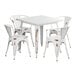 A Lancaster Table & Seating distressed pearl white metal dining table with four white arm chairs.