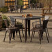 A Lancaster Table & Seating copper outdoor table with four chairs on a stone patio.