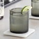 Two Acopa gray old fashioned glasses filled with whiskey and lime wedges.