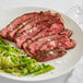 A plate with Warrington Farm Meats flank steak and vegetables on a white table.