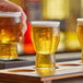 A person holding a tray of Rastal Craft Master Grand beer tasters on a table in a brewery tasting room.