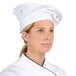 A woman wearing a white Chef Revival chef beret.