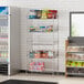 A Regency chrome storage rack with baskets holding snacks and beverages in a convenience store.