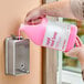 A person pouring Advantage Chemicals liquid soap into a soap dispenser.