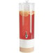 A Cal-Mil blonde plastic beverage dispenser with red liquid and lemon slices.