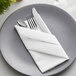 A white cloth napkin wrapped around a knife and fork.