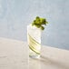 An Arcoroc Essentials Collins Glass filled with water and garnished with a cucumber slice.