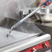 A person using a Scrubble by ACS griddle squeegee to clean a griddle.