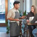 A man and woman in Acopa denim aprons talking to a woman at a table.