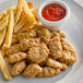 A plate of Beleaf Plant-Based Vegan Chicken Nuggets and french fries with a bowl of ketchup.