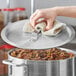 A hand using a towel to clean a Choice domed aluminum pot lid.