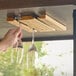 A hand removing a wine glass from a Fox Run wood glass rack with slots.