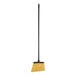 A Carlisle commercial broom with a black pole and yellow bristles.