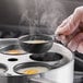 A person cooking eggs in a Choice 12-Cup Egg Poacher Set.