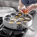 A person putting eggs into a Choice 12-Cup Egg Poacher set.