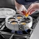 A person putting eggs into a Choice Egg Poacher pan on a stove.