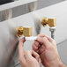 A person using a Regency wall mount faucet to fill a white plastic cup.