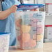 A woman holding a Vigor translucent blue polypropylene food storage container filled with peppers.