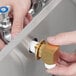 A person's hands installing a Regency wall mount faucet with a swivel gooseneck spout over a kitchen sink.