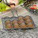 An Outset grill basket with meatballs cooking on a grill.