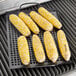 Outset non-stick grill tray with corn on the cob cooking on a grill grate.