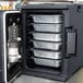 A granite gray Cambro front loading food pan carrier with trays of food inside.