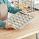 A person holding a Baker's Mark glazed aluminized steel mini muffin pan full of muffins.