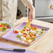 A person cutting vegetables on a Baker's Mark purple sheet pan.