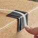 A person holding a black plastic strapping edge protector box.