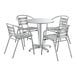 A white metal table with a white surface and four silver arm chairs.