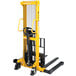 A yellow and black Vestil manual hydraulic fork stacker with black handle.