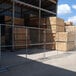 A chain link fence with stacks of wood in a fenced area.