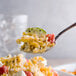 A spoonful of Regal medium egg noodles with tomatoes and cheese.