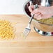 A hand holding a fork over a bowl of Regal medium egg noodles.