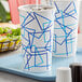 A close up of a white Choice paper cold cup with a blue and white geometric design.