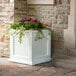 A white square planter with purple flowers and green leaves.