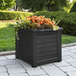 A black Mayne Lakeland planter with flowers in it.