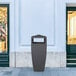 A black Mayne Kobi decorative waste bin in front of a store.