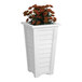 A white Mayne Lakeland planter with orange flowers in it.