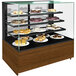 A Structural Concepts non-refrigerated bakery display case on a counter with cakes and pastries on it.