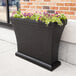 A black rectangular Mayne trough planter with flowers in it.