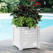 A white Mayne Lakeland planter with green plants.